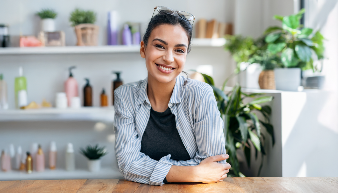 The owner of a success beauty business sits at her desk looking happy because her back end systems and software are working hard for her business.